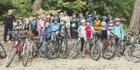 Powiększ grafikę: Grupa uczniów wraz z nauczycielkami na wycieczce rowerowej w lesie. 