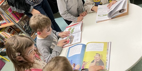 Powiększ grafikę: Goszczące w szkole dzieci zapoznają się z księgozbiorem w szkolnej bibliotece.