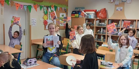 Powiększ grafikę: Uczniowie klasy 4a trzymają w rękach książkę "Gdańsk dla młodych podróżników".