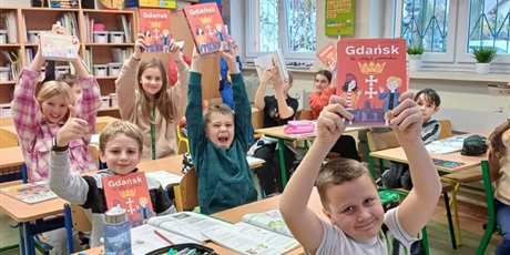 Powiększ grafikę: Uczniowie klasy 4b trzymają w rękach książkę "Gdańsk dla młodych podróżników".