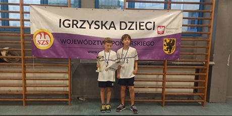 Powiększ grafikę: Dwójka chłopców z medalami i pucharem stoi pod transparentem Igrzyska Dzieci Województwa Pomorskiego.