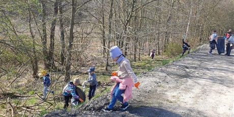 Powiększ grafikę: Grupa dzieci sprząta najbliższą okolicę szkoły - las z zalegających tam śmieci.
