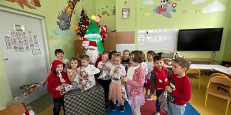 Powiększ grafikę: Dzieci z zerówki pozują do zdjęcia ze Św. Mikołajem i prezentem.