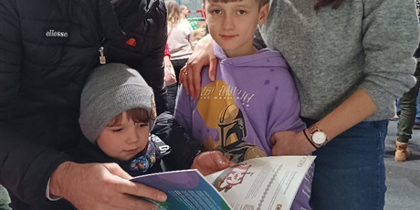 Powiększ grafikę: Dwoje chłopców z rodzicami przegląda broszury dotyczące Unii Europejskiej.