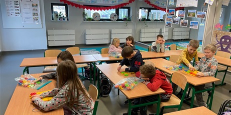Powiększ grafikę: Dzieci siedzą w klasie przy stolikach parami i w parach kodują z wykorzystaniem klocków KORBO.
