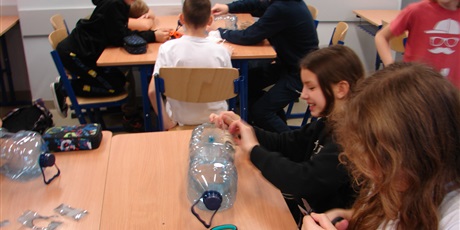 Powiększ grafikę: Uczennice z plastikowej butelki po wodzie wykonują karmnik dla ptaków.