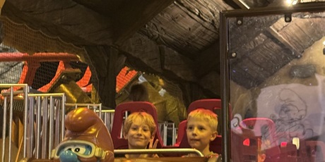 Powiększ grafikę: Dwóch chłopców jedzie w wagoniku z figurką Papy Smerfa z przodu.