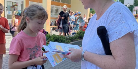 Powiększ grafikę: Pani Bibliotekarka wręcza  dziewczynce nagrodę - dyplom i kartę podarunkową za wysoki wynik w Wielkim Maratonie Czytelniczym - 3 miejsce.