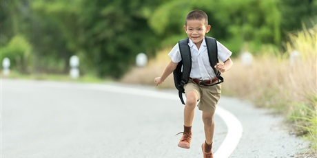 Powiększ grafikę: Chłopiec z plecakiem ubrany na galowo biegnie ulicą.