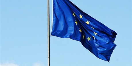 Powiększ grafikę: Flaga Unii Europejskiej powiewa na tle nieba.