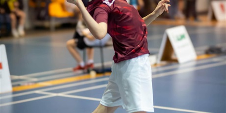 Powiększ grafikę: Uczeń w wyskoku z rakietką odbija lotkę w badmintonie.